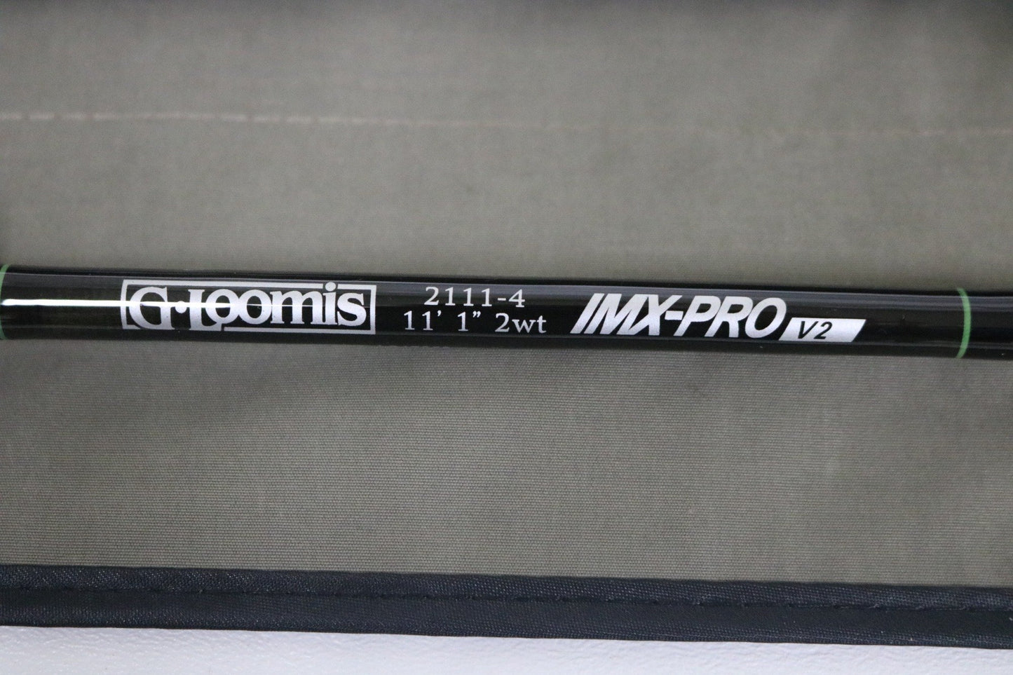 A close-up of a G. Loomis IMX-PRO V2 Shortspey 2111-4 11'1" #2 used fly rod in mint condition, set against a beige background—great for those interested in used gear or our Rod and Reel Trade-In Program.