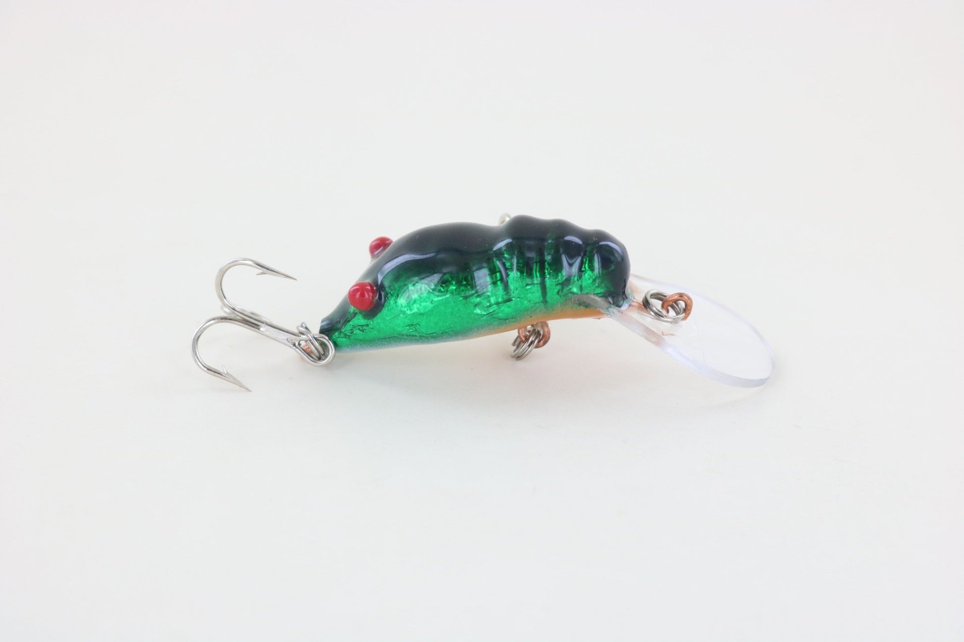 The WE Baits Red Eye Craw Green Foil is a green and black fishing lure with red eyes and two treble hooks from WE Baits, displayed on a plain white background.