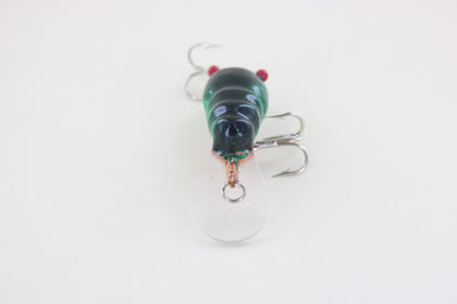 A close-up of the WE Baits Red Eye Craw Green Foil fishing lure by WE Baits, featuring a green and black finish, clear plastic lip, and treble hooks, displayed on a plain white background.