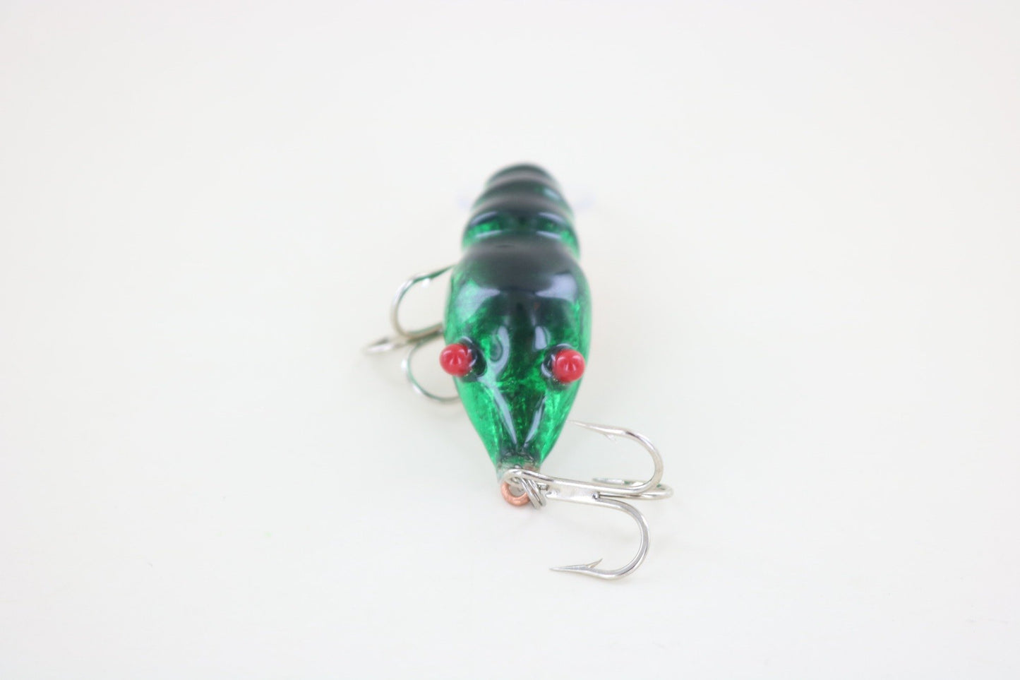 The WE Baits Red Eye Craw Green Foil by WE Baits, a green shrimp-shaped fishing lure with red eyes and two silver treble hooks, is shown on a plain white background.