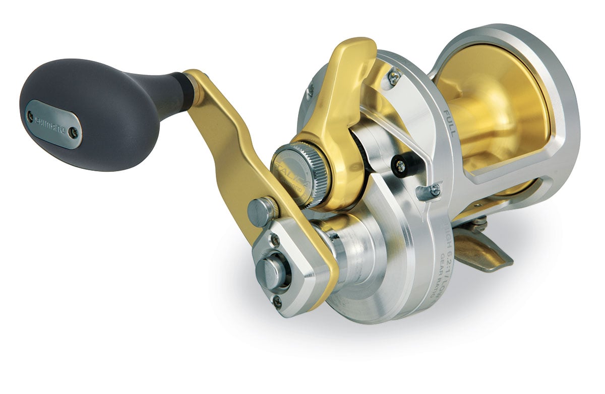 The Shimano Talica TAC10II 2 Speed Lever Drag Reel by Shimano, featuring a gold and silver finish with a black handle, is designed for heavy-duty use and high-speed power and is shown on a white background.