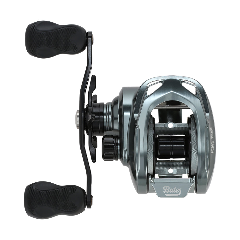 Top-down view of a metallic gray Bates Fishing Co. Hundo'50 Casting Reel 6.3:1 LH (BRH50LH631) with two black handles, center spool, and the "Bates Fishing Co." brand name visible on the front.