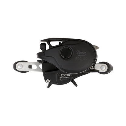Close-up of a Bates Fishing Co. EDC 100 Casting Reel 7.1:1 RH (BREDC100RH711) in black and silver, showing detailed levers and dials, photographed against a plain white background.