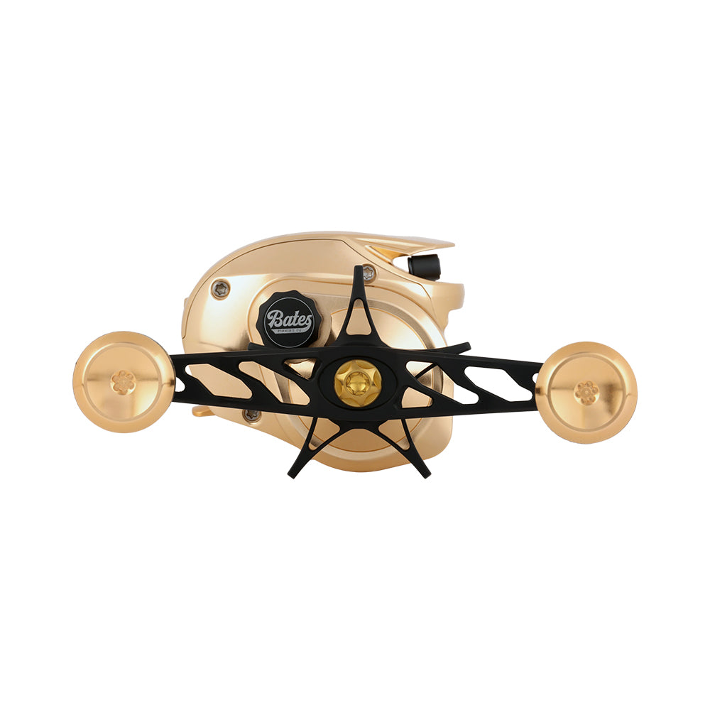 The Bates Fishing Co. GOAT SWM LE Knox Gold Casting Reel 5.2:1 RH features a sleek gold and black CNC machined aluminum design with two large gold handles, making it an ideal premium casting reel.