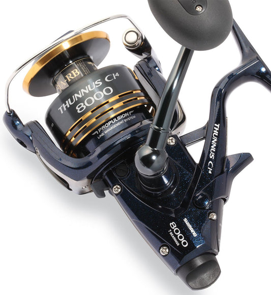 Close-up of the Shimano Thunnus 8000CI4 Saltwater Spinning Reel by Shimano, showcasing its lightweight design, spool, handle, and distinctive brand markings on a blue and gold metallic finish.