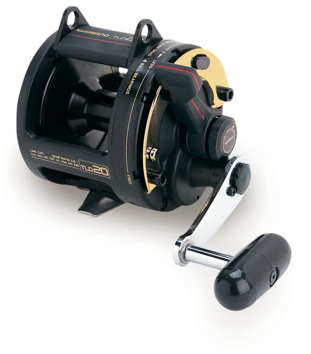 A close-up of the Shimano TLD 20 Lever Drag Fishing Reel by Shimano, featuring a black and gold design with a silver crank handle and black grip, set against a white background.