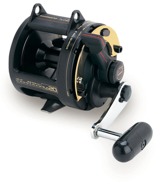 A close-up of the Shimano TLD 20 Lever Drag Fishing Reel by Shimano, featuring a black and gold design with a silver crank handle and black grip, set against a white background.