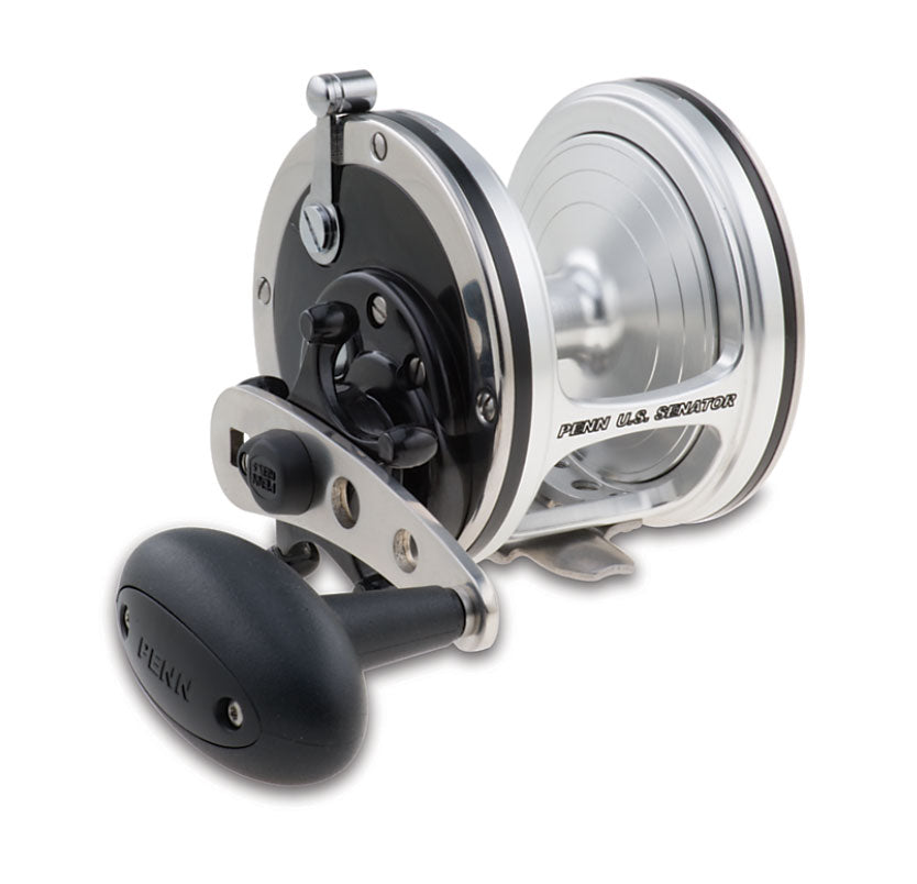 The Penn US Senator Conventional Fishing Reel US113W, in silver and black, is shown from the side with its large handle, visible gears and spool. The "PENN" brand name appears on the handle and side plate. Made in USA.